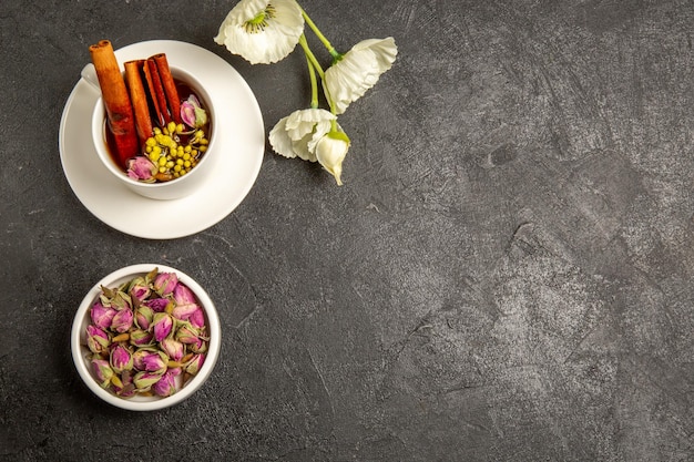 Draufsicht Tasse Tee mit Blumen und Zimt auf grauem Hintergrund Teefarbe Regenbogengeschmack