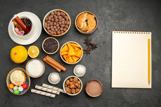 Kostenloses Foto draufsicht tasse tee mit chips und kuchen auf dunkler oberfläche kekse süßigkeiten keks kuchen kuchen süß