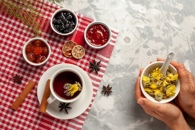 Draufsicht Tasse Tee mit Dessert und verschiedenen Marmeladen auf hellweißem Backgruond-Fruchtmarmeladentee süßem Zucker