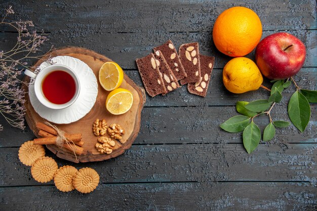 Draufsicht Tasse Tee mit Früchten und Süßigkeiten auf dem dunklen Tisch