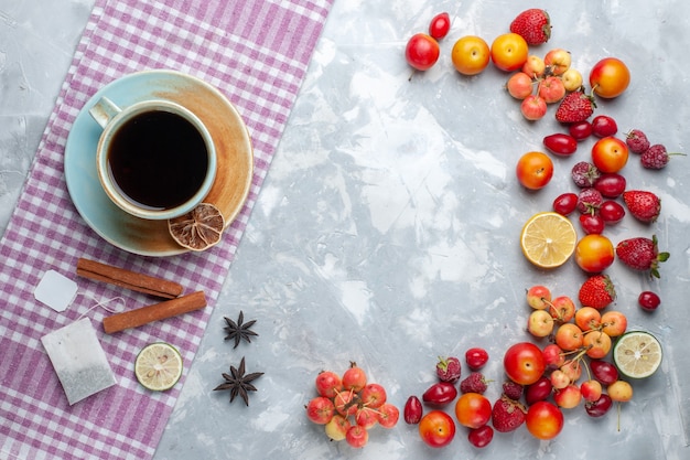 Draufsicht tasse tee mit früchten zimt auf leichtem schreibtisch obstbeere frisches vitamin