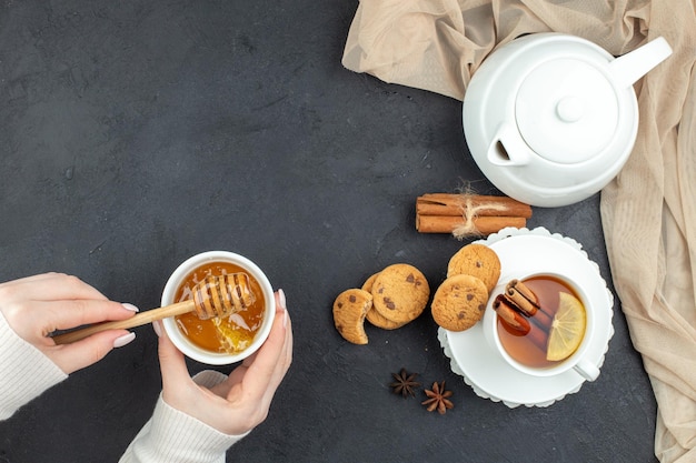 Draufsicht Tasse Tee mit Honig und Keksen auf dunklem Hintergrund Mittagessen Zeremonie Frühstück Lebensmittelfarbe Zitronenplätzchen weiblich