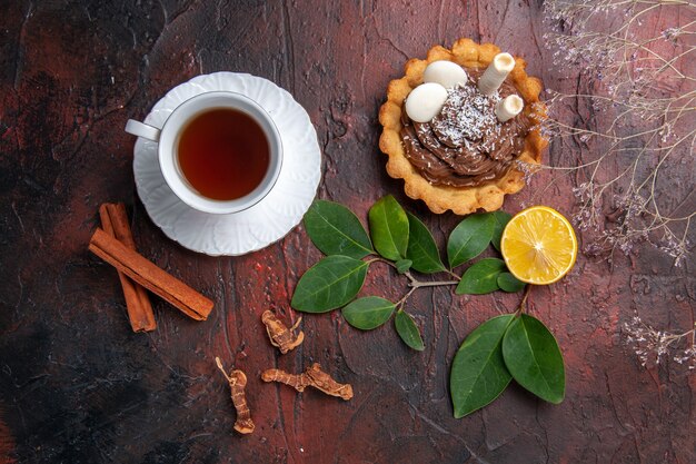 Draufsicht Tasse Tee mit köstlichem kleinen Kuchen auf dunklen Tischkeksdessertkeksen