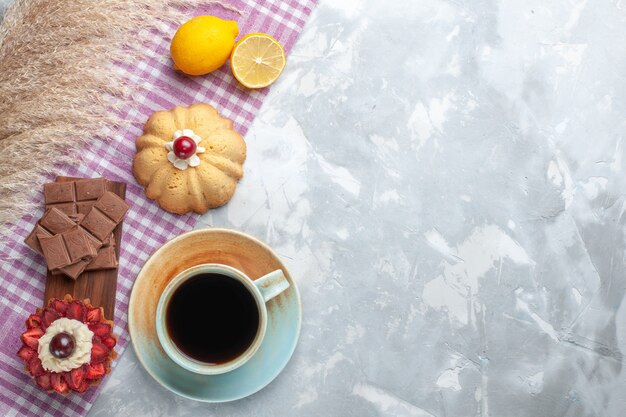 Draufsicht Tasse Tee mit Kuchen Zitrone und Schokoriegel auf dem weißen Schreibtisch Kuchen süße Zuckerschokolade