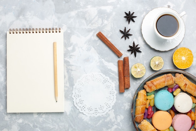 Draufsicht tasse tee mit macarons bagels auf weiß