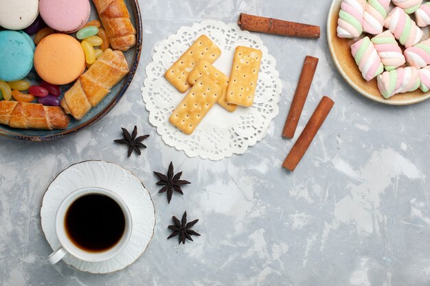 Draufsicht Tasse Tee mit Macarons Bagels auf Weiß