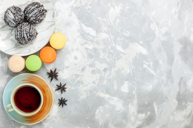 Draufsicht Tasse Tee mit Macarons und Schokoladenkuchen auf weißem Schreibtisch backen Kuchenkekszuckersüßkuchen