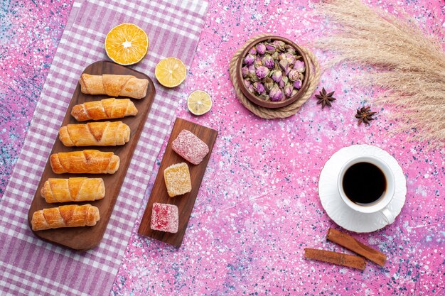 Draufsicht Tasse Tee mit Marmeladenstücken und Bagels auf dem rosa Boden.