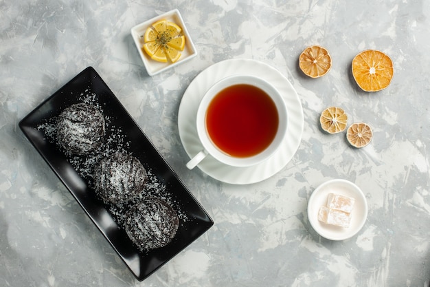 Draufsicht tasse tee mit schokoladenkuchen auf hellweißem schreibtisch