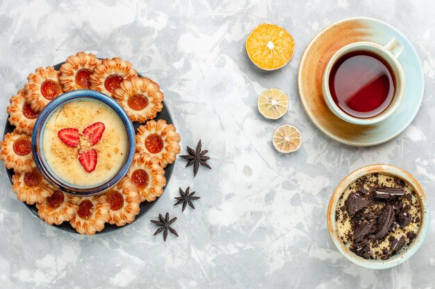 Draufsicht Tasse Tee mit Schokoladenplätzchen-Dessert und Marmeladenplätzchen auf hellweißem Schreibtischplätzchen-Schokoladenkuchen backen Kuchenzucker süß