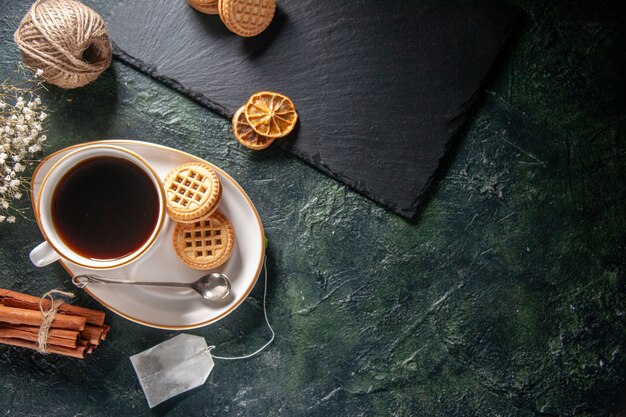 Draufsicht Tasse Tee mit süßen Keksen auf dunklem Hintergrund