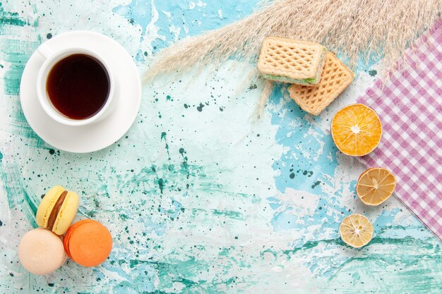 Draufsicht Tasse Tee mit Waffeln und französischen Macarons auf dem blauen Hintergrund Kekse Kekszucker süße Kuchen Torte