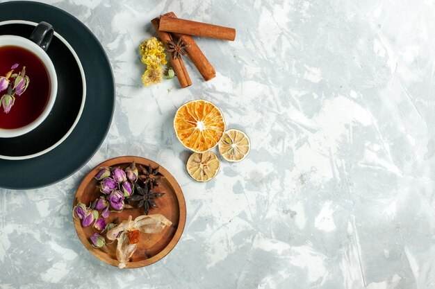 Draufsicht Tasse Tee mit Zimt und Blumen auf hellweißer Oberfläche Tee süßes Getränk Blume