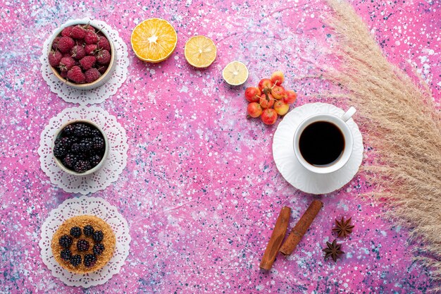 Draufsicht Tasse Tee mit Zimtbeeren und Kuchen auf dem hellrosa Hintergrund.