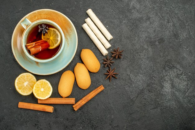 Draufsicht Tasse Tee mit Zitrone und Keksen auf dem dunklen Hintergrund