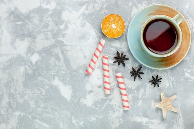 Draufsicht Tasse Tee mit Zitrone und Süßigkeiten auf hellweißem Hintergrund Süßigkeiten Frucht süßer Tee