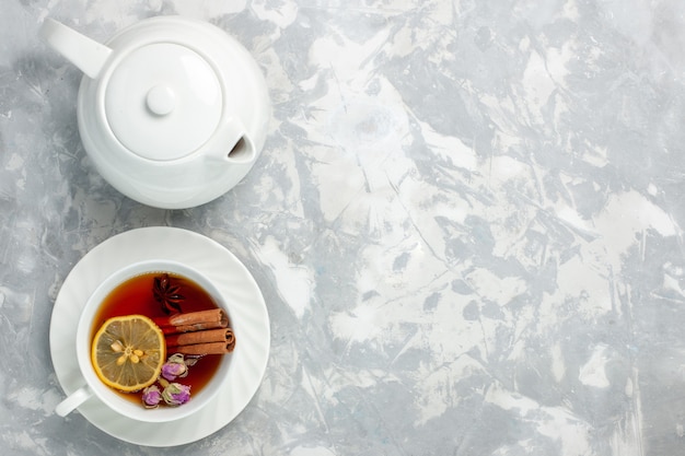 Draufsicht Tasse Tee mit Zitrone und Zimt auf der hellweißen Oberfläche