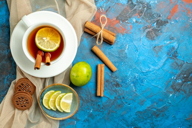 Draufsicht Tasse Tee mit Zitrone und Zimtbeige Schal Kekse Zitrone auf blau-roter Oberfläche kopieren Platz