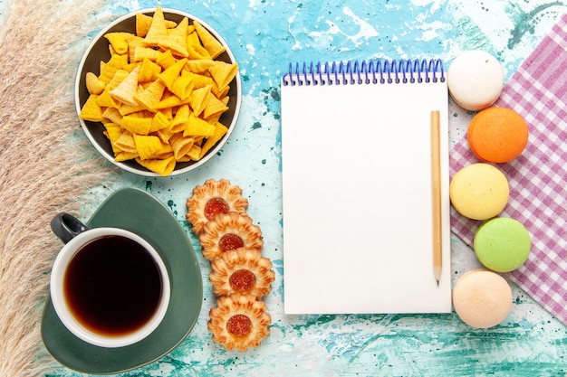 Kostenloses Foto draufsicht tasse tee mit zuckerplätzchen macarons und chips auf hellblauem hintergrundplätzchenkekszucker süßer teekuchenkuchen