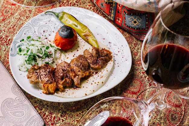 Draufsicht Tika Kebab auf Fladenbrot mit gegrilltem Gemüse und Zwiebeln und einem Glas Wein