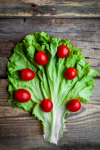 Draufsicht-Tomaten auf Salat auf dunklem hölzernem Hintergrund. Vertikale