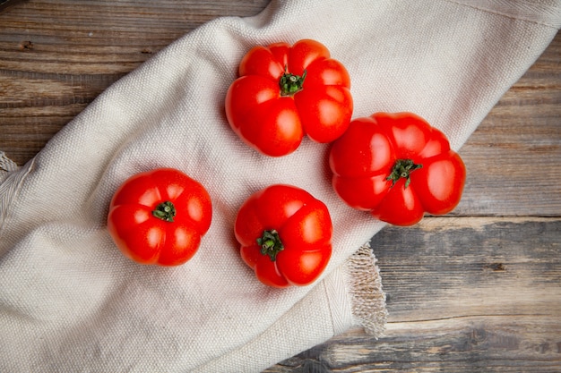 Draufsicht-Tomaten auf weißem Stoff und dunklem hölzernem Hintergrund. horizontal