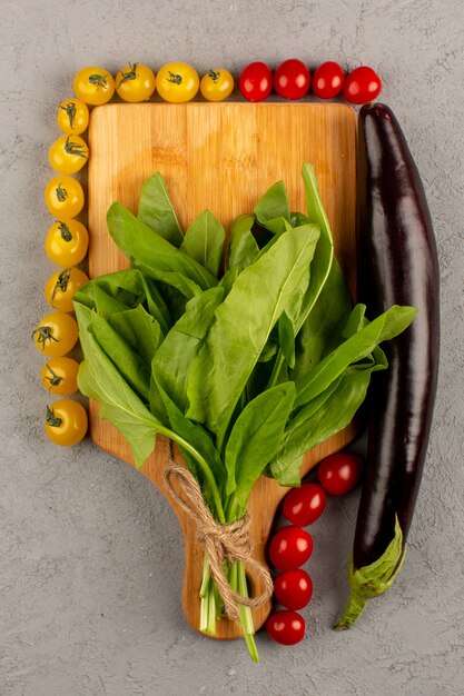 Draufsicht Tomaten gelb und rot zusammen mit Auberginen und grünen Blättern auf grauem Boden