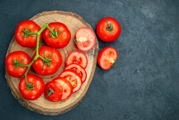Draufsicht Tomatenzweig auf Holzbrett gehackte Tomaten dunklen Hintergrund