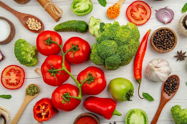 Draufsicht Tomatenzweig Brokkoli rote Paprika Holzlöffel Knoblauch Pilz Holzlöffel auf grauem Hintergrund