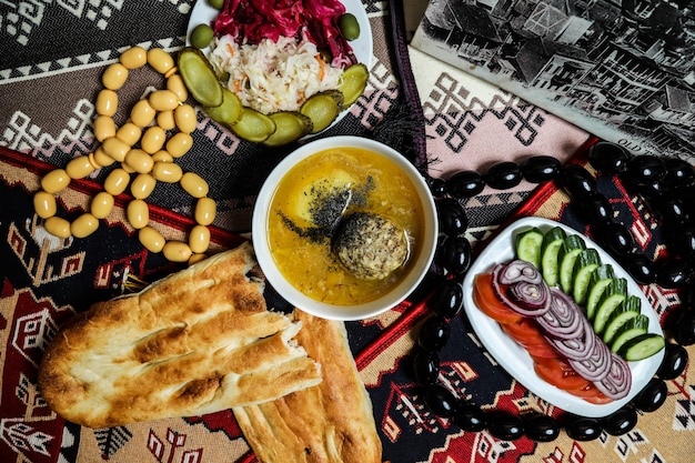 Draufsicht traditionelles aserbaidschanisches Gericht Kyufta Bozbash mit Tomatengurken und Zwiebeln mit Tandirbrot auf dem Tisch