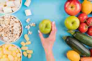 Kostenloses Foto draufsicht ungesundes vs gesundes essen mit hand, das apfel hält