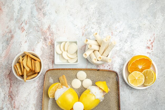 Draufsicht vereiste Zitronen mit Bonbons und Crackern auf weißem Tisch