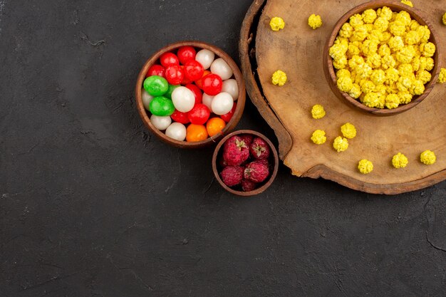 Draufsicht verschiedene Bonbons bunte Bonbons auf dem dunklen Schreibtisch Bonbonfarbe Regenbogenzucker