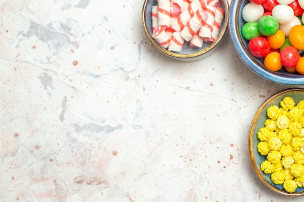 Kostenloses Foto draufsicht verschiedene bonbons mit konfitüren auf weißem tischsüßigkeiten regenbogenzucker