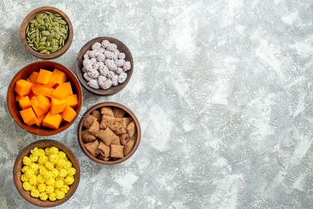 Kostenloses Foto draufsicht verschiedene bonbons mit samen auf weißer oberflächenblumenfarbe bonbontee