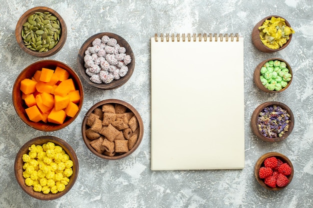 Kostenloses Foto draufsicht verschiedene bonbons mit samen und kürbis auf weißer oberflächenblumenfarbe bonbontee