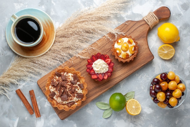 Draufsicht verschiedene cremige Kuchen fruchtige Kuchen mit Zitronenkirschentee auf weißem Schreibtischkuchen backen Keks süße Zuckerfrucht