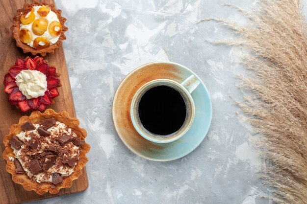 Draufsicht verschiedene cremige Kuchen mit Schokolade und Früchten zusammen mit Tee auf dem weißen Schreibtischkuchen backen Keks süße Zuckerfrucht