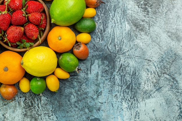 Kostenloses Foto draufsicht verschiedene frische früchte mit roten erdbeeren auf grauem hintergrund