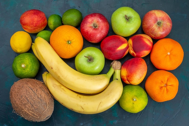 Kostenloses Foto draufsicht verschiedene fruchtzusammensetzung bananen mandarinen äpfel auf dunkelblauem schreibtisch