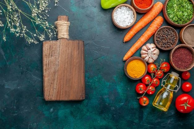 Draufsicht verschiedene Gewürze mit frischen Tomaten auf dunkelgrünem Schreibtischzutatprodukt Mahlzeitlebensmittelgemüse