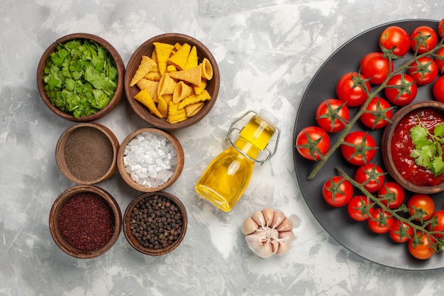 Draufsicht verschiedene Gewürze mit Kirschtomaten auf weißem Schreibtisch