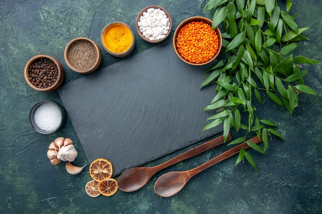 Draufsicht verschiedene Gewürze mit Knoblauch und orange Linsen auf dunkelblauem Hintergrundfoto Essen würzige scharfe Paprika Farbe scharfe Samensuppe