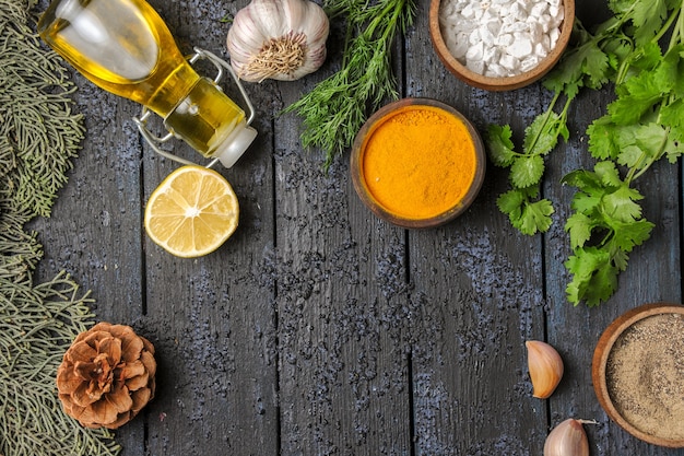 Draufsicht verschiedene Gewürze mit Öl und Knoblauch auf dunklem Schreibtisch