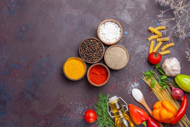 Draufsicht verschiedene Gewürze mit roher Pasta auf dunklem Hintergrund Rohkostsalat Gesundheit Diät Pasta