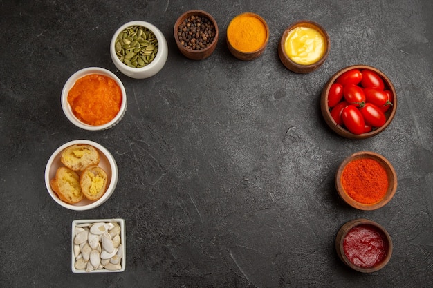 Draufsicht verschiedene gewürze mit tomaten auf dunklem hintergrund farbe pfeffer würzige frucht