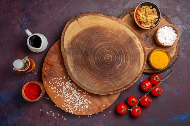 Draufsicht verschiedene Gewürze mit Tomaten auf dunklem Hintergrund Mahlzeit Essen Gewürz würzig