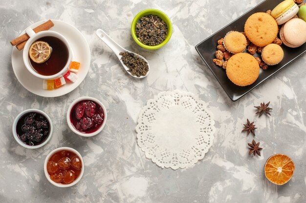 Draufsicht verschiedene Kekse mit Marmeladen und einer Tasse Tee auf dem weißen Schreibtischkekszuckerkuchen-süßen Keks