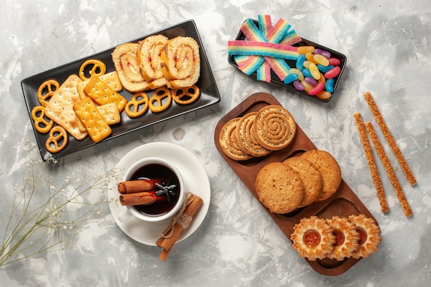 Draufsicht verschiedene Kekse mit Süßigkeiten und Tasse Tee auf weißer Oberfläche Kekse Kekszucker backen Kuchen süße Torte