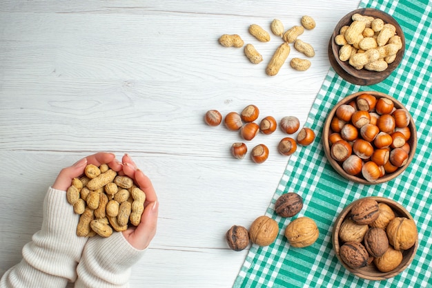 Draufsicht verschiedene Nüsse Erdnüsse Haselnüsse und Walnüsse auf weißem Tisch in der Hand